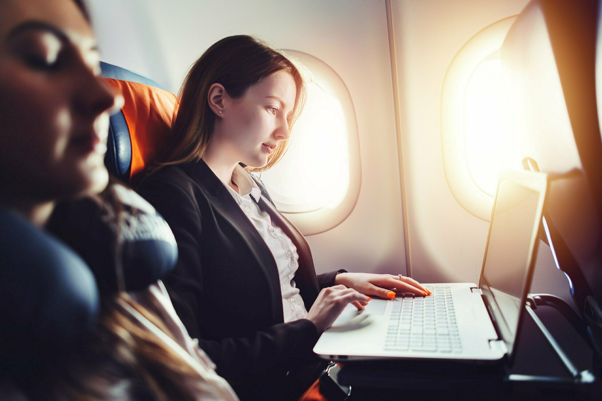 Corporate traveller working on laptop sitting near window in an airplane